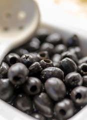 Close up of fresh and organic pitted black olives on a luxury Greek buffet with a serving spoon