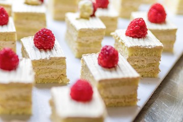 Close up of raspberrys on cream cakes or sweet dessert slices on a luxury gourmet buffet