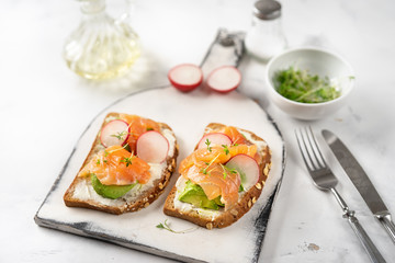 Two toasts with avocado, radish and salmon. Healthy eating
