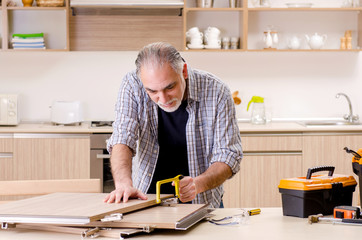 Aged contractor repairman working in the kitchen 