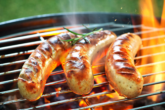 Delicious sausages sizzling over the coals on barbecue grill