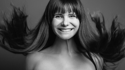 Organic hair care cosmetic products. Black and white closeup portrait of emotional brunette girl jumping happy to have healthy strong locks.