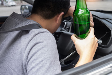 Don't Drink for Drive concept, Young Drunk man drinking bottle of beer or alcohol during driving the car dangerously