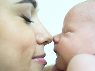 Obraz premium mom touches her nose on the nose of a sleeping newborn baby close-up