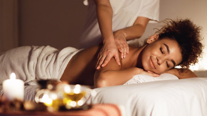 African-american girl enjoying relaxing back massage in spa