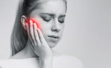 Young woman suffering from tooth pain, caries