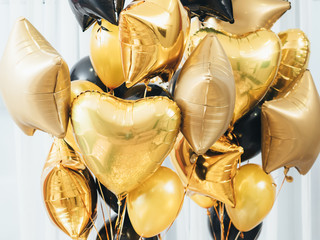 Party decoration. Festive interior. Closeup of golden and black round, heart, star shaped balloons...