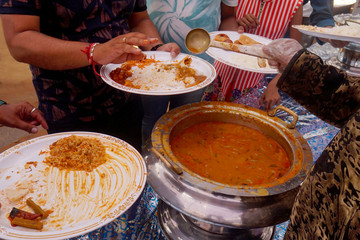 Closeup of Indian street food vendor serving vegetable curry from  bowl
