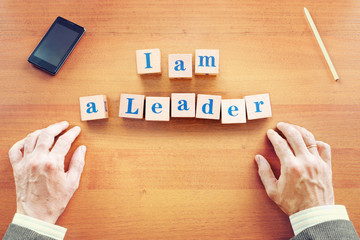 I am a leader. Businessman made text from wooden cubes on a desk