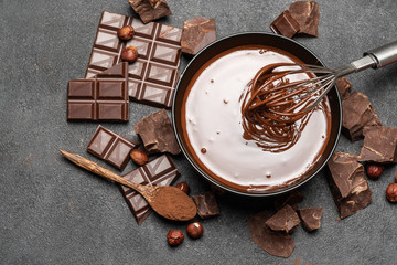 ceramic bowl of chocolate cream or melted chocolate and pieces of chocolate on dark concrete...