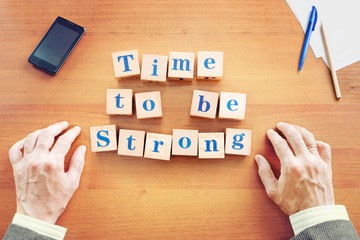 Time to be strong. Businessman made text from wooden cubes on a desk