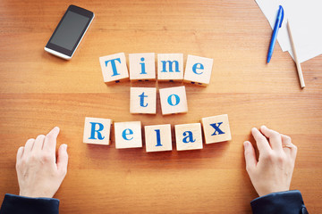 Time to relax. Business woman made text from wooden cubes on a desk