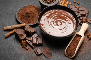 ceramic bowl of chocolate cream or melted chocolate and pieces of chocolate isolated on dark concrete background