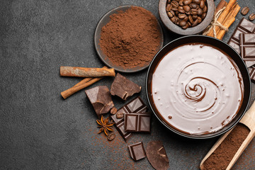 ceramic bowl of chocolate cream or melted chocolate and pieces of chocolate isolated on dark concrete background