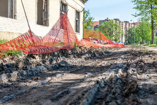 Tire Track Print In The Mud And Dirt After Wheel Earth Mover Or Bulldozer Construction Digger Machinery Finish With Work In The City Street With Orange Safety Net Or Fence Low Point Of View 