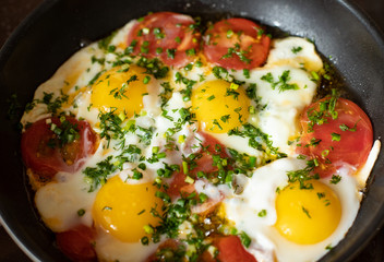 Fried eggs in a pan with tomatoes and herbs for Breakfast close-up