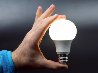 human hand holding the included led lamp on a dark background
