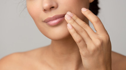 Woman applying lip balm over grey background