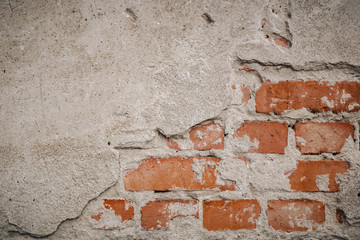 Red brickwork underneath concrete wall. Textured suface. Half painted wall. Background. Cracks and roughness.