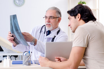 Fototapeta premium Young man visiting old male doctor radiologist 