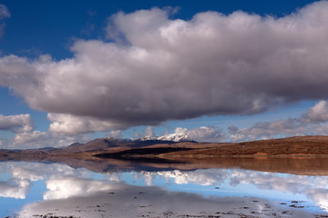 Snow white peaks enfold by lovely cloudscape and reflections