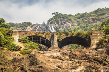 Fototapeta na wymiar Railway bridge over the river Mandovi on the background of the Dudhsagar waterfall