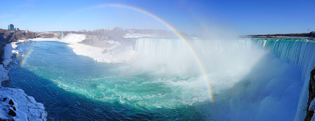 Rainbow over the Horseshoe Falls over frozen ice and snow on the Niagara River in Niagara Falls in March 2019