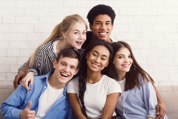 Happy diverse friends relaxing on comfortable couch in apartment