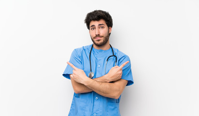 Surgeon doctor man over isolated white wall pointing to the laterals having doubts