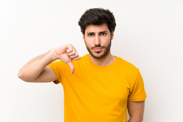 Handsome over isolated white wall showing thumb down sign