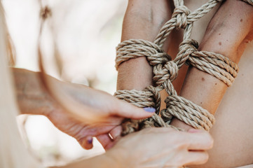 Woman bound with a rope in Japanese technique shibari outdoors