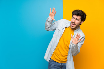 Handsome over isolated colorful background nervous and scared