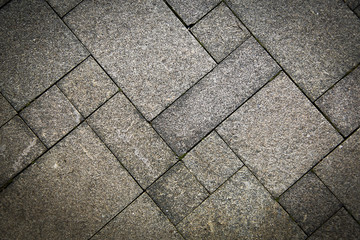 The sidewalk road made of natural stone is lined with mosaics of light gray color .Texture