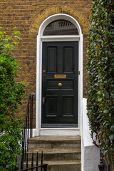Black Wooden Entrance Door to residential building in London. Typical door in the English style.