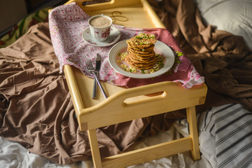Fototapeta na wymiar tasty breakfast in bed from eastern pancakes and Masala tea, served on the wood folding breakfast table