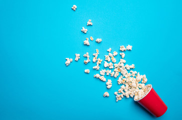 Pop corn scattered on blue color background, top view