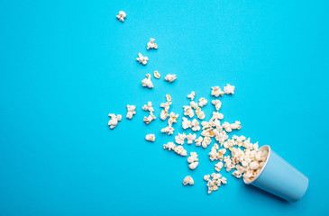 Pop corn scattered on blue color background, top view