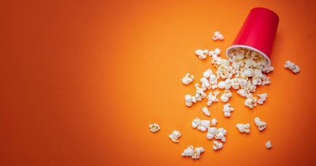 Pop corn scattered on orange color background, top view