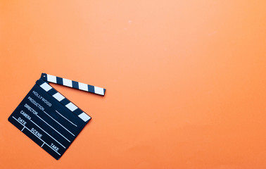 Movie clapperboard on orange color background, top view