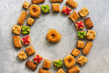 Middle Eastern traditional dessert baklava on a gray background. Round frame of arabic sweets. Overhead view
