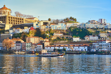 Fototapeta na wymiar Boats on Douro river with view on Red roofs of side Villa Nova de Gaia in Porto. Concept of world travel, sightseeing and tourism