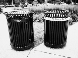 regular and recycling trash bins in a park in black and white