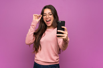 Teenager girl over purple wall making a selfie