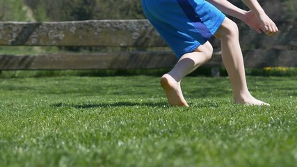 boy on the grass kicking football in garden - slow motion - Powered by Adobe