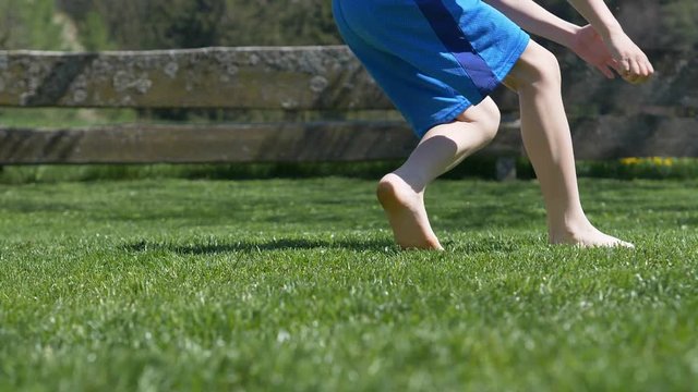 boy on the grass kicking football in garden - slow motion
