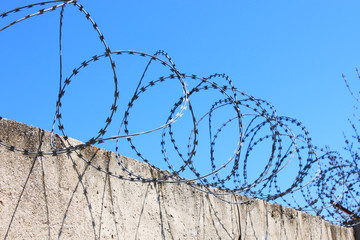 Barbed wire on fence with blue sky, the concept of prison, salvation, copy space.