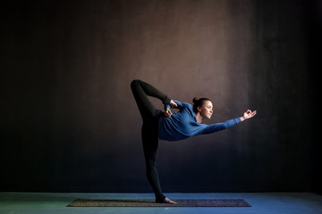 Woman practicing yoga, stretching in Natarajasana exercise