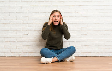 Young woman sitting on the floor with surprise expression