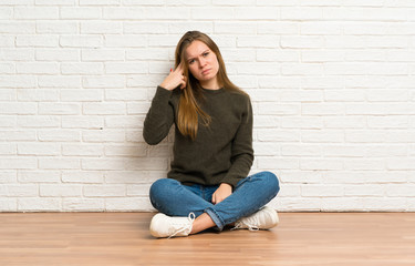 Fototapeta na wymiar Young woman sitting on the floor with problems making suicide gesture