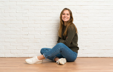 Young woman sitting on the floor with arms crossed and looking forward